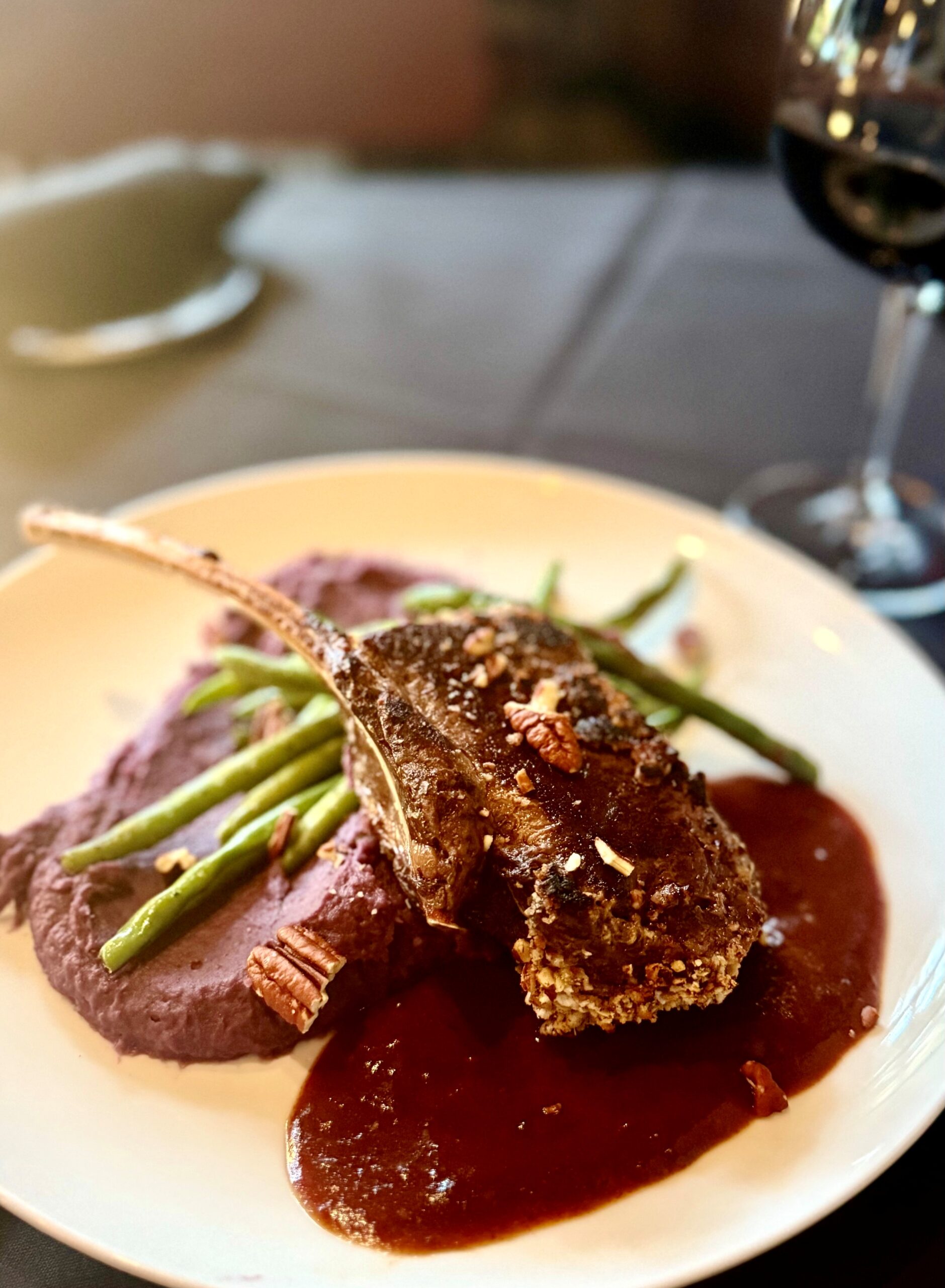 Pecan-crusted bone-in New Zealand venison loin chop with date demi, green beans, and whipped purple sweet potatoes at The Tasting Room in Traverse City