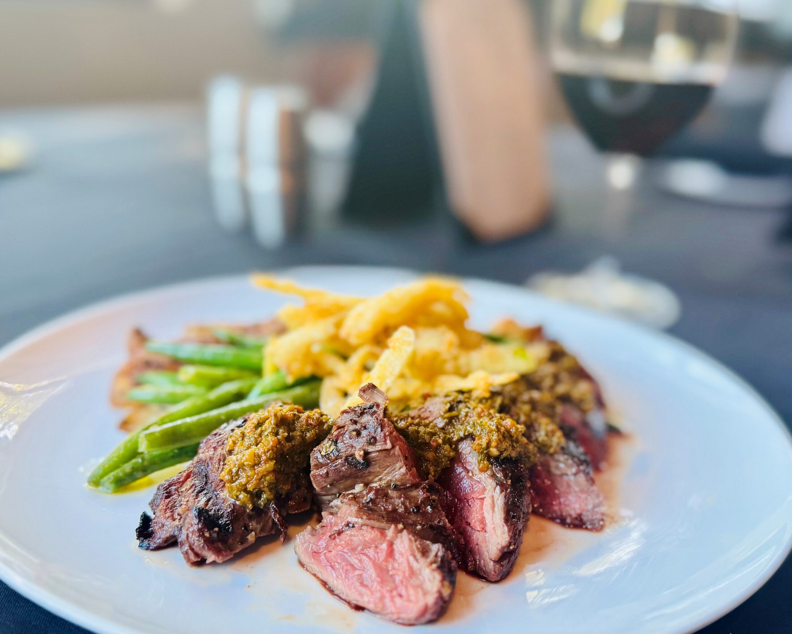 Six-ounce buffalo hanger steak with chimichurri, pesto green beans, roasted red skin potatoes, and crispy fried leeks — The Tasting Room in Traverse City