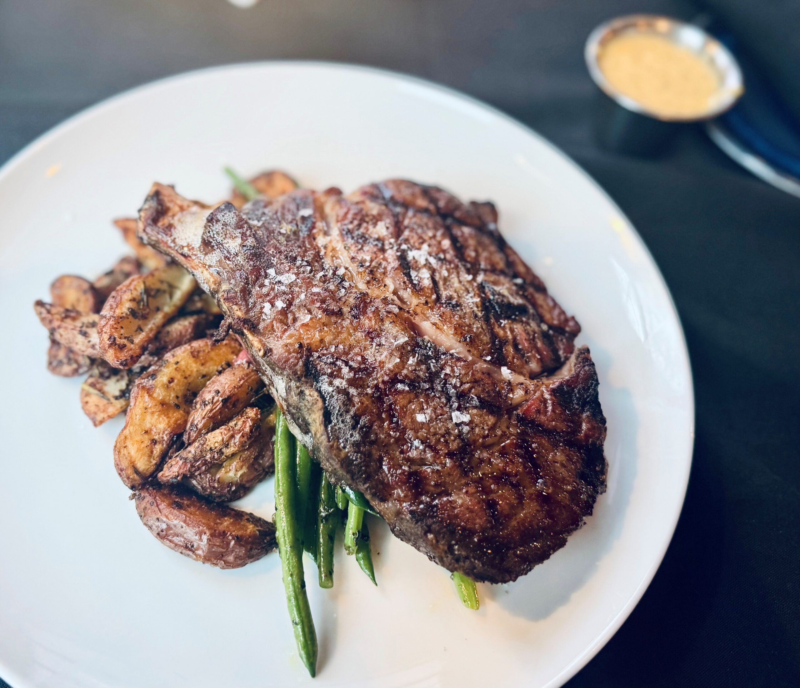 Steakhouse bone-in ribeye with truffle Béarnaise, roasted potatoes, and green beans at The Tasting Room in Traverse City